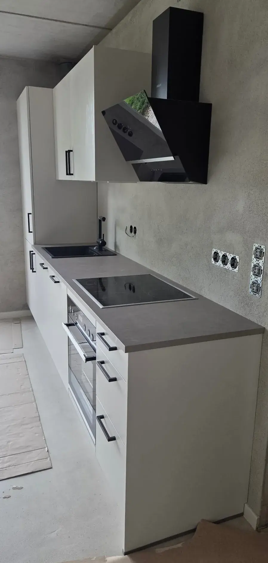 Moderne Einbauküche mit Herd, Backofen und schwarzer Dunstabzugshaube.