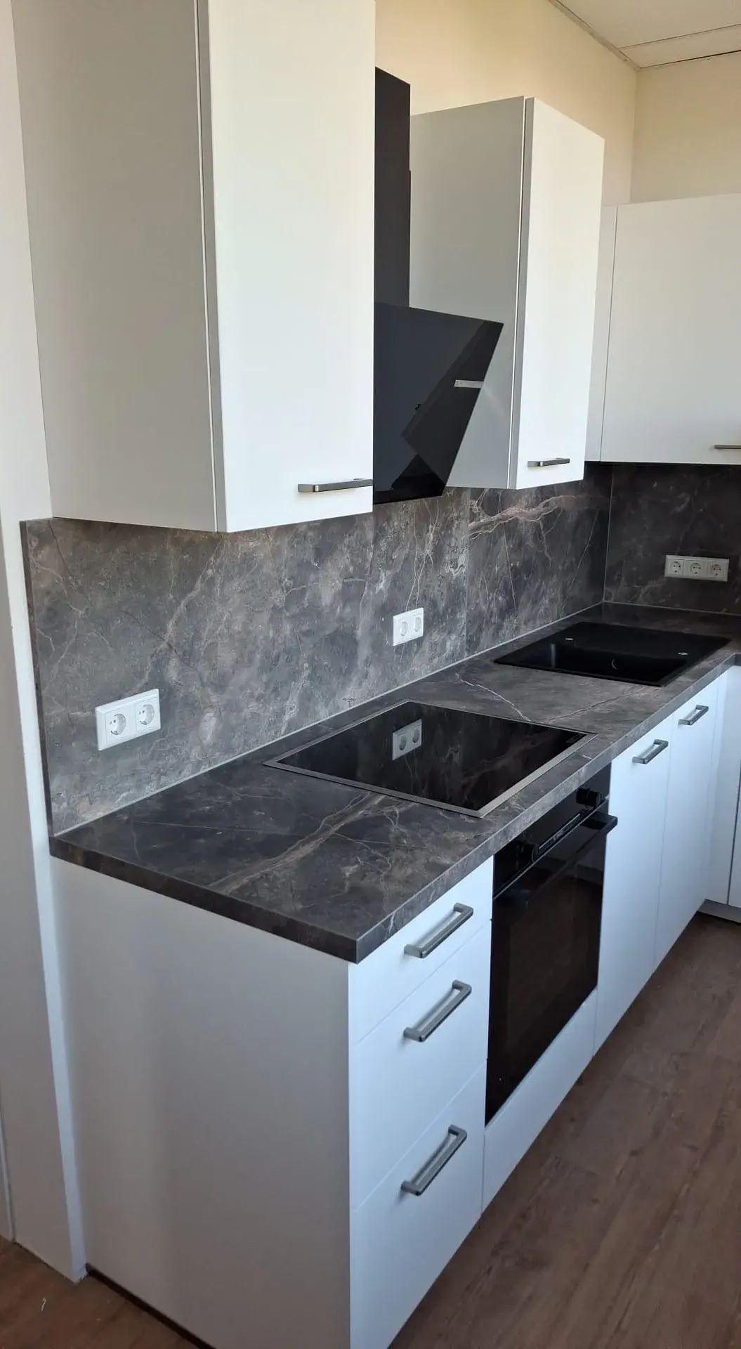 Küchenraum, weiße Küche, Marmor Dekor Arbeitsplatte, Schwarzer Backofen, Schwarze Haube, Holzboden